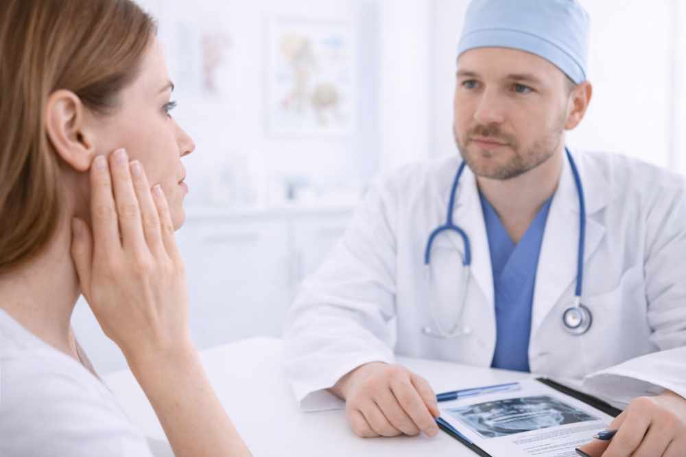 консултация с лицево-челюстен хирург – пациент обсъжда болка в челюстта с лекар